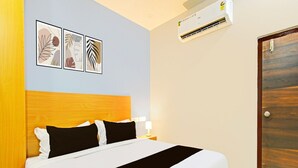 Et hotelværelse med en seng, et træhovedgærde, en fastmonteret aircondition og en dør.