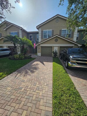 A residential building with a brick driveway, a garage, and a flag. - 3-bedrooms townhouse in lovely Verandah Fort Myers Florida (Fort Myers)