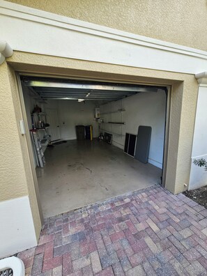 Eine Garage mit Betonboden, einem Ziegelweg, der davor führt, und einer weißen Tür.