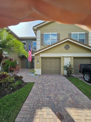 Ein Wohnhaus mit Garage, einer amerikanischen Flagge und einer Auffahrt aus Ziegelsteinen.