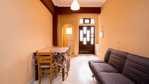 A room with a dining table, chairs, a sofa, a light fixture, and a door with windows. - Southgate 3 by MPS (Agios Georgios)