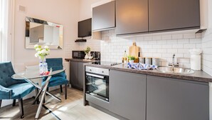 A modern kitchen with a dining area, built-in appliances, and a flat-screen TV. - Bright Studio | Walk to City | Washer & Dryer (Dublin)