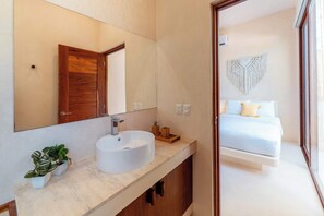 A modern bathroom with a large mirror, a white sink, and wooden cabinets. - Ahal Holistika 3BR Oasis with Plunge Pool (Tulum)
