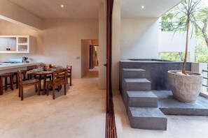 A modern kitchen with wooden furniture, a dining area, and a large potted plant. - Ahal Holistika 3BR Oasis with Plunge Pool (Tulum)
