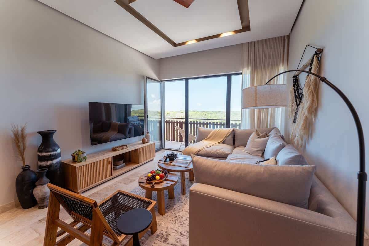 A modern living room with a TV, sofa, coffee table, and large windows.