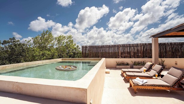 Una piscina en la azotea con sillones de descanso y una pérgola.