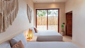 Un dormitorio con dos camas, un colgador de macramé en la pared, una lámpara de noche y vistas a una valla de bambú.