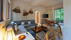 A modern living room with a sofa, coffee table, and dining area. - Stylish Ground-Floor 3BR Haven ,Luxe Plunge Pool (Tulum)