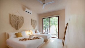 A bedroom with two beds, a ceiling fan, and a large window. - Stylish Ground-Floor 3BR Haven ,Luxe Plunge Pool (Tulum)