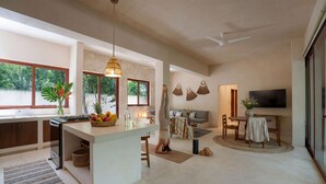 A spacious living area with a kitchen island, a dining table, and a TV. - Stylish Ground-Floor 3BR Haven ,Luxe Plunge Pool (Tulum)