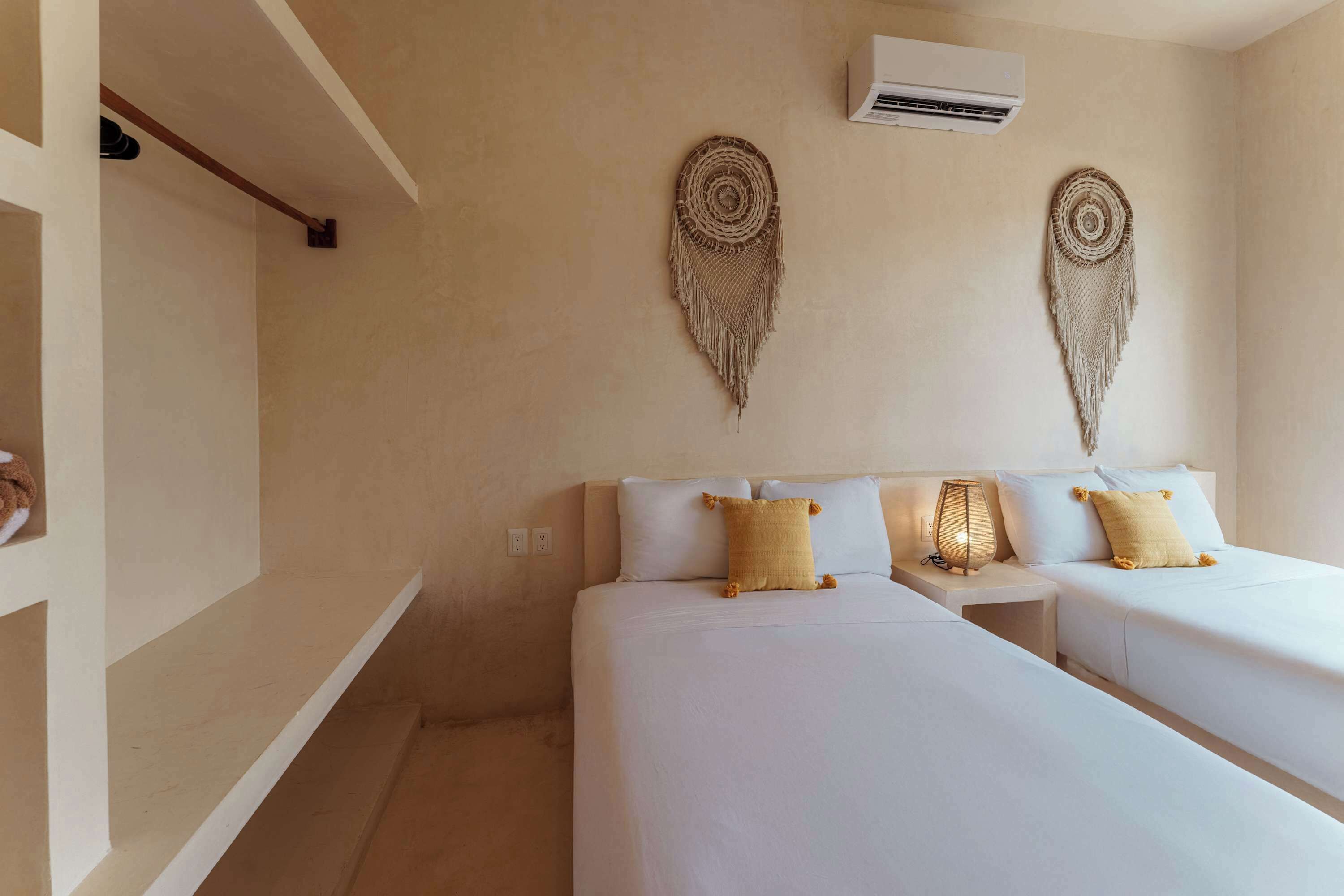 Quarto de hotel com duas camas, ar condicionado fixado na parede e decorações nas paredes.