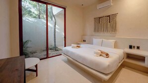 Ein modernes Schlafzimmer mit einem großen Bett, einem kleinen Schreibtisch und einer Glasschiebetür, die auf einen Balkon führt.