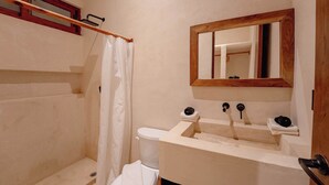 Ein Badezimmer mit Dusche, Toilette, Waschbecken und Spiegel.
