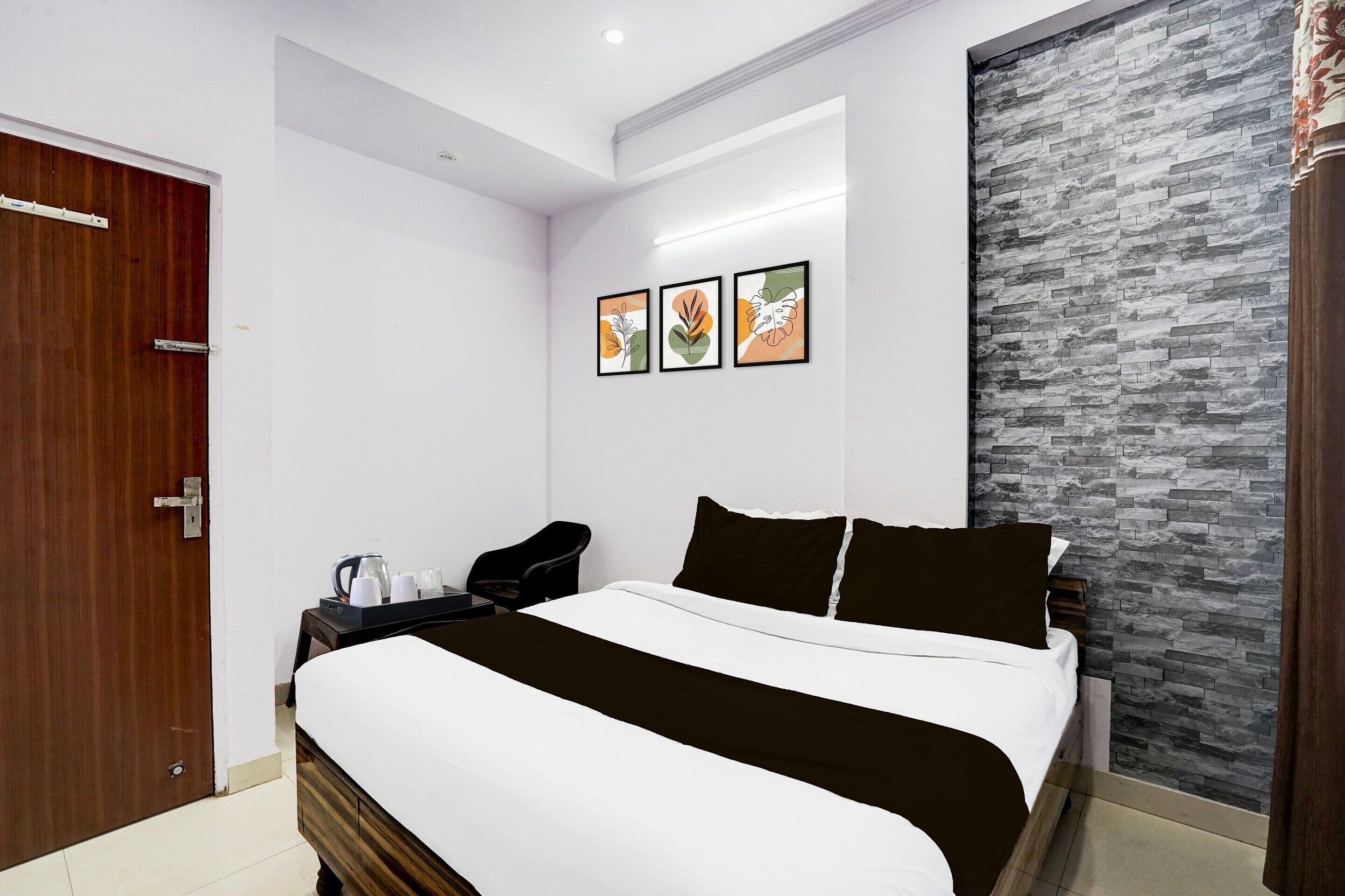 A bedroom with a bed, a desk, a chair, and a wall-mounted artwork.
