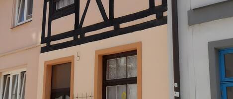Un edifici amb el número 5 a la façana, una finestra amb un disseny de graella i una porta amb reixatge.