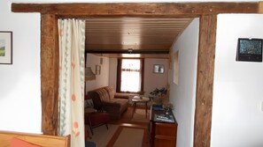 Un salón acogedor con un sofá, una mesita con un jarrón y techo de madera.