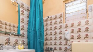 A bathroom with a sink, toilet, shower, and a window with a metal screen. - Southgate 4 by MPS (Agios Georgios)