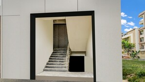 Een modern gebouw met een centrale trap, een klein afgesloten gedeelte beneden en een heldere lucht.