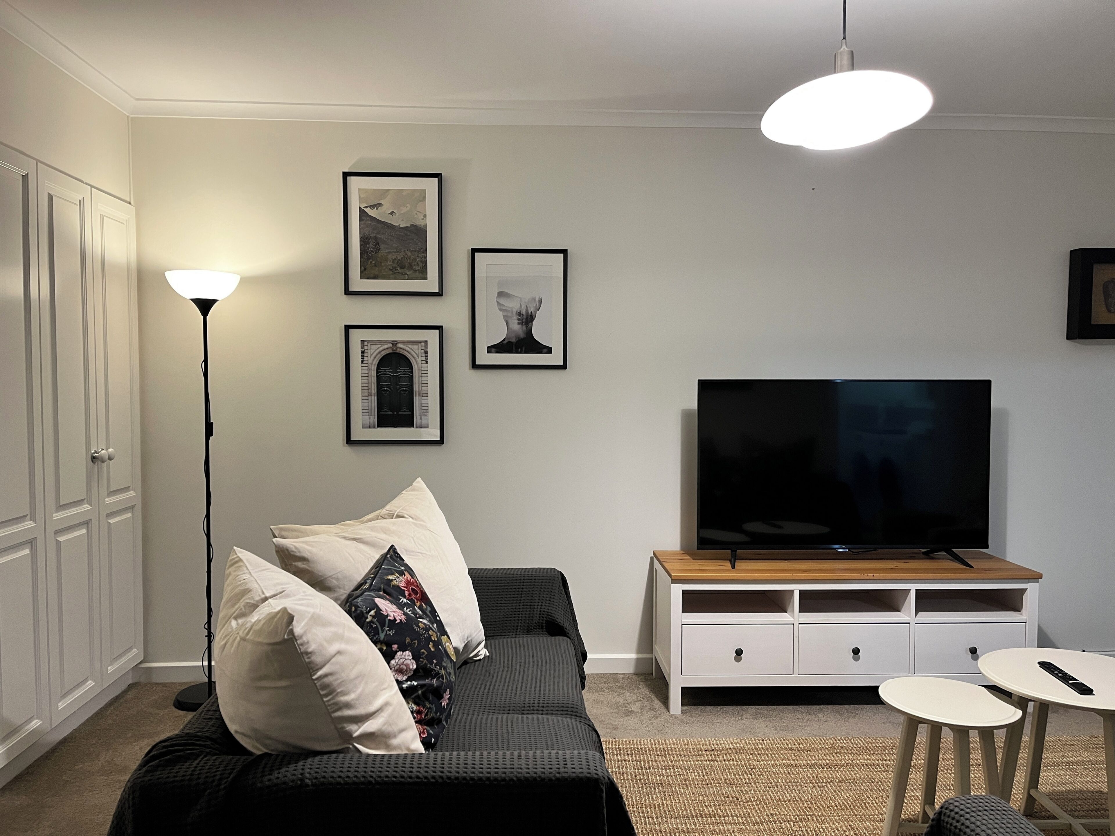 A living room with a sofa, a TV, a lamp, and framed pictures on the wall.