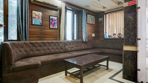 A room with a brown leather sofa, a wooden wall with framed pictures, and a 'No Smoking' sign. - Deluxemahipalpur Near Airport (New Delhi)