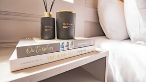A bedside table with books, a candle, and a diffuser.