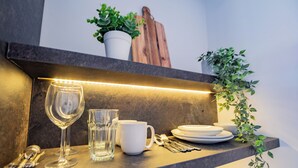 A kitchen counter with a wine glass, a mug, plates, and utensils.