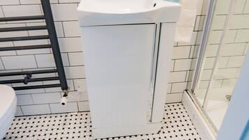A bathroom with a white sink, a towel rack, and a shower area.