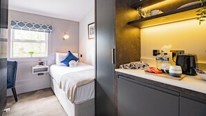 A bedroom with a bed, bedside table, and a window with blinds.