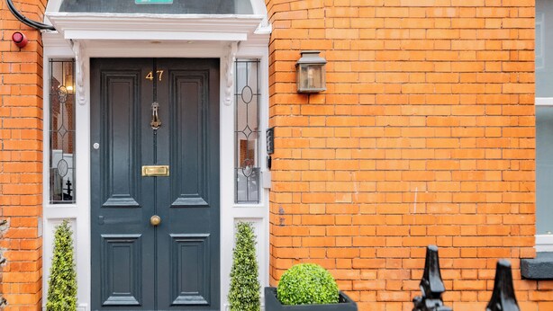 A black door with the number 47, a white-framed window, and a checkered floor pattern.