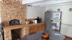 A kitchen with a stone wall, wooden cabinets, a built-in oven, and a round table with chairs. - Vacation home with private pool (Banon)