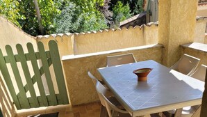 A patio with a table and chairs, a green fence, and a tiled floor. - Vacation home with private pool (Banon)