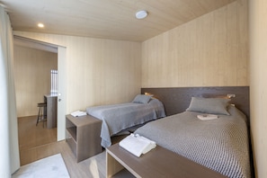 Quarto com duas camas, uma escrivaninha e uma cadeira.