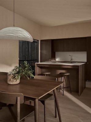 Uma cozinha moderna com ilha central, mesa de jantar de madeira e banquetas de bar.