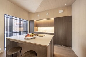 Uma cozinha moderna com ilha central, armários de madeira, uma janela com persianas e uma pia embutida.