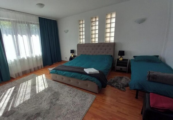 Une chambre à coucher avec un lit, des tables de chevet, un tapis et une fenêtre avec des rideaux.