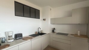 Uma cozinha moderna com armários brancos, bancada preta, pia, cafeteira e torradeira.
