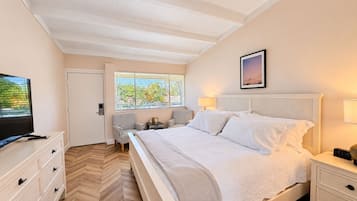 Una camera d'albergo con un letto, comodini, televisione, una scrivania e sedie, e una finestra con persiane.