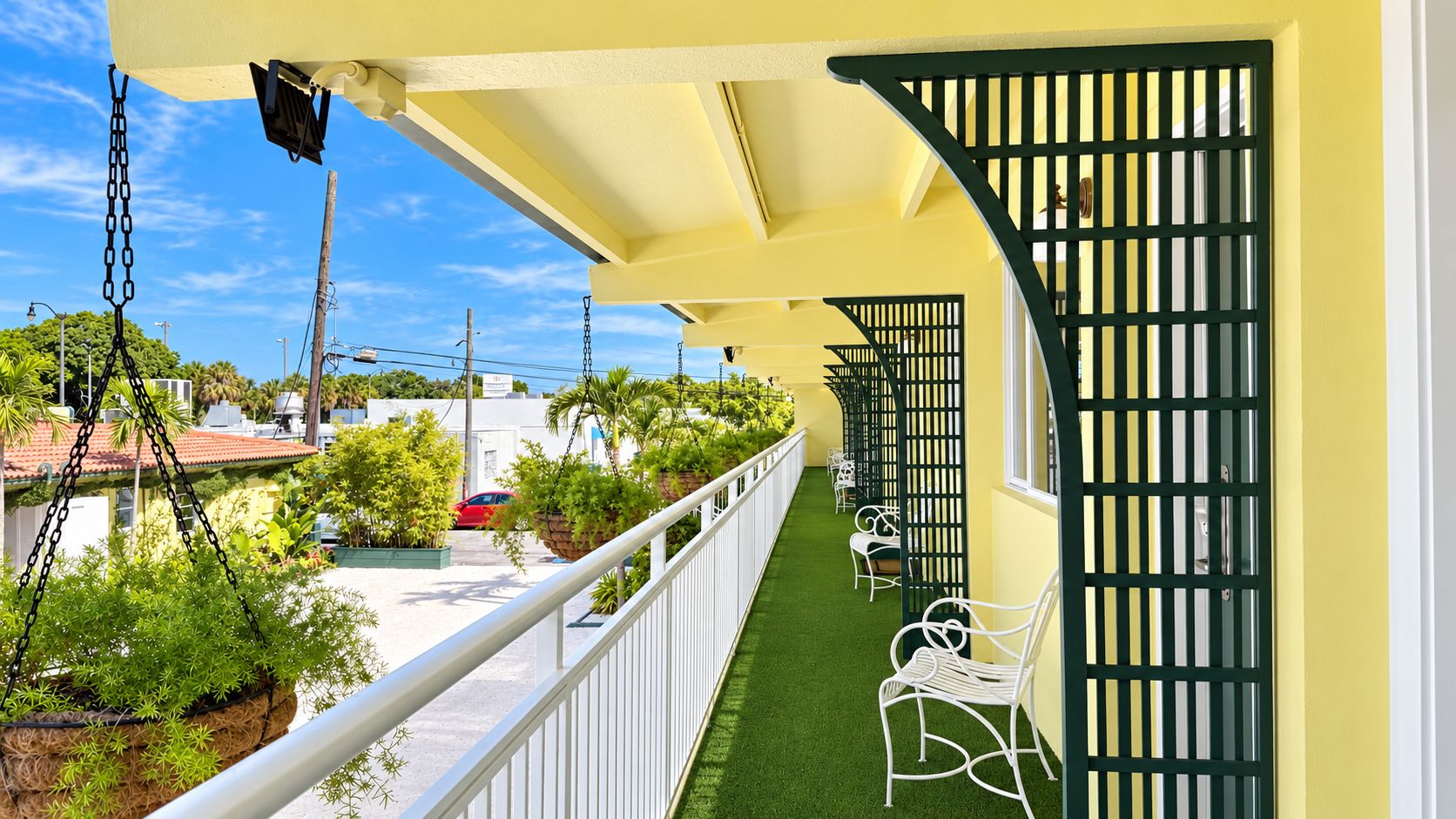A balcony with a white railing, green artificial grass, and white chairs.