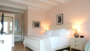 A bedroom with a bed, bedside lamps, a nightstand, and a framed picture on the wall.