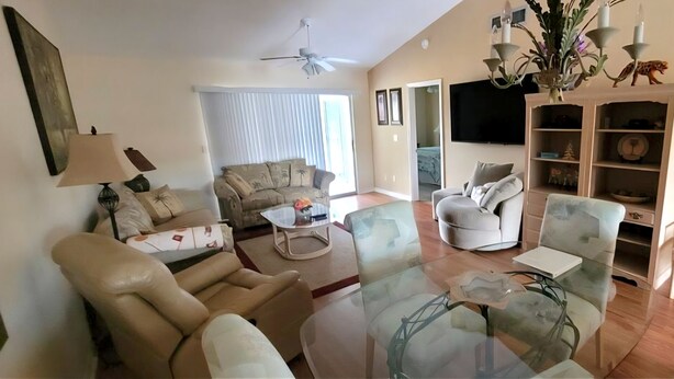 Una sala de estar con un sofá, sillones, una mesa de centro de cristal, un televisor y una estantería.