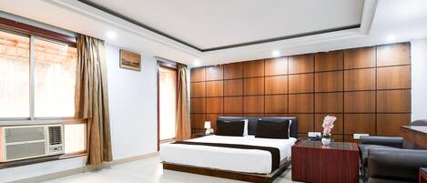 A modern hotel room with a large bed, a desk, and a view of the outdoors.