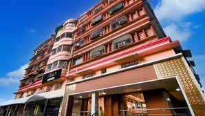 A multi-story hotel with balconies, a sign indicating a restaurant, and a clear blue sky. - Deluxealandur Near Chennai Airport (Dhanbad)