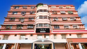 A multi-story building with balconies, a sign indicating a company service, and a gated entrance. - Deluxealandur Near Chennai Airport (Dhanbad)