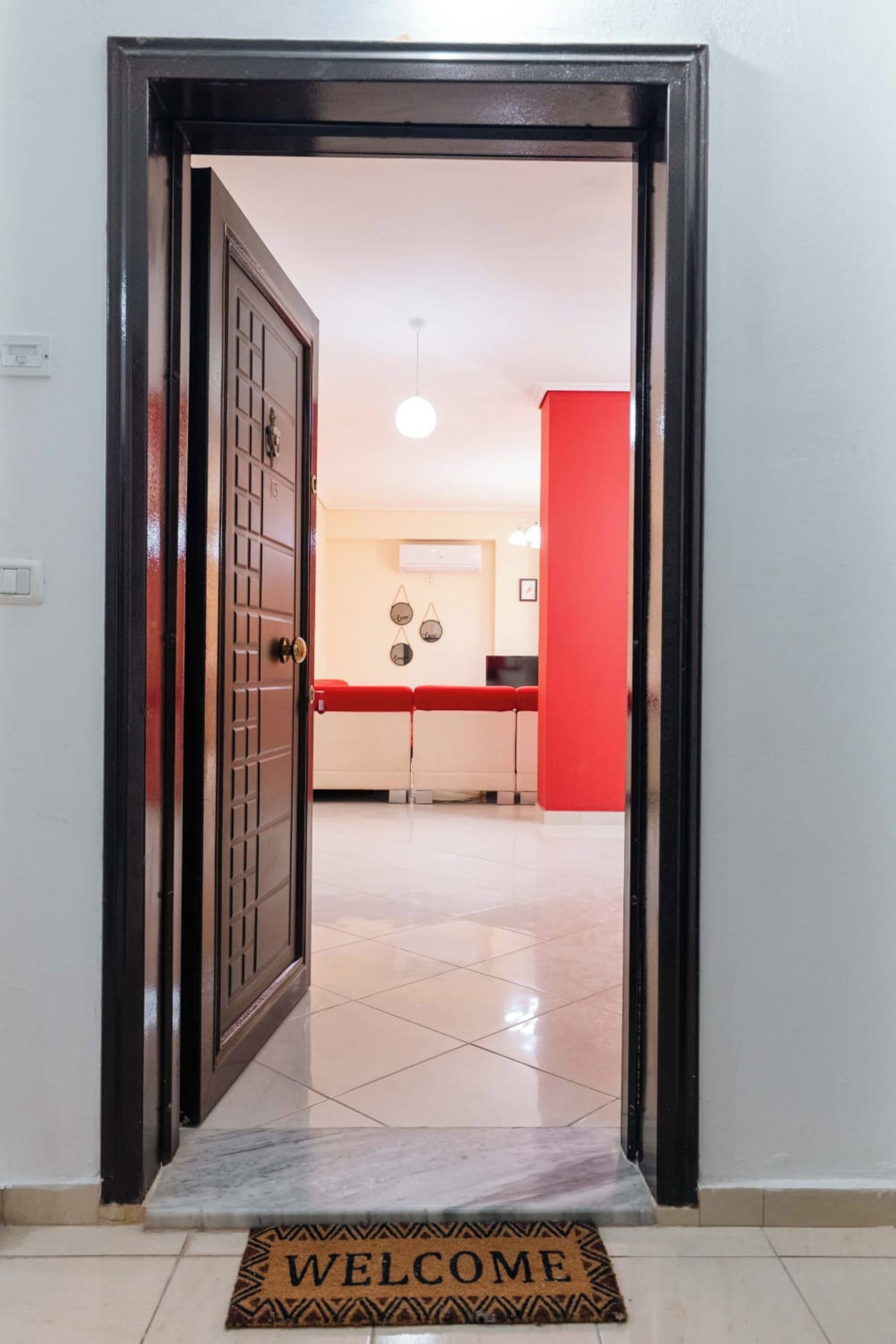 A doorway leading to a room with a tiled floor and a red accent wall.