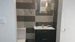 A compact bathroom with a toilet, sink, and mirror. - TROPICAL BUNGALOW (Gros-Morne)