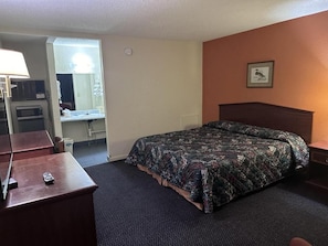A hotel room with a bed, a desk, a lamp, a mirror, and a framed picture on the wall. - Crystal Motel (Tulsa)