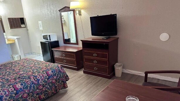 Quarto de hotel com cama, cómoda de madeira, televisão, secretária e cadeira.