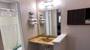 Casa de banho com lavatório, espelho, porta-toalhas e cortina de chuveiro.