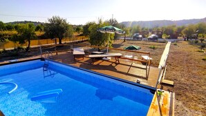 A swimming pool with a wooden deck, lounge chairs, and umbrellas. - Feudo Mallav b&b Noto (Avola)