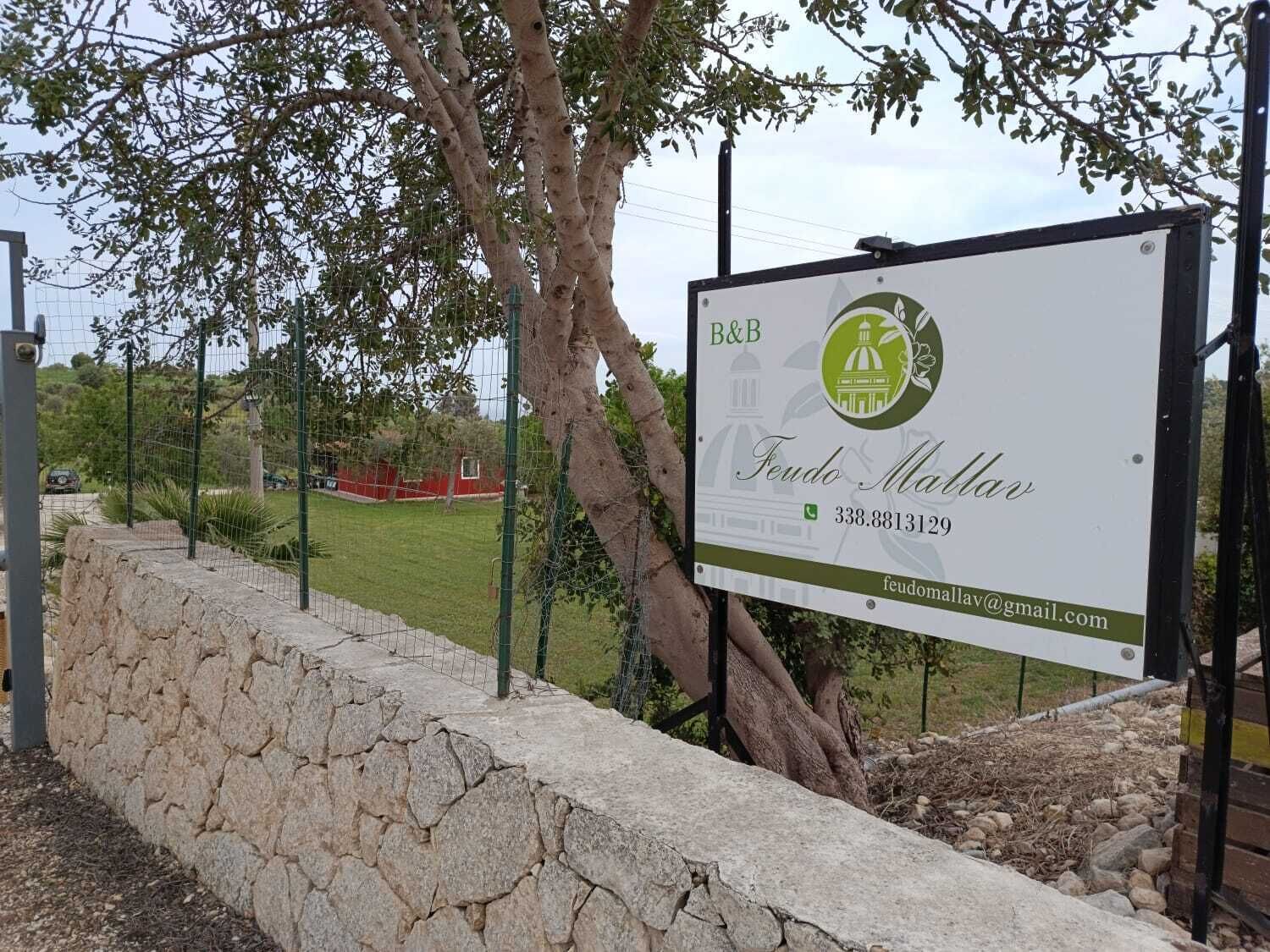 A signboard with the name 'Feudo Mallar' and contact information.